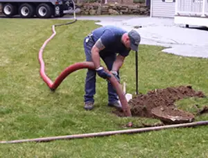Septic pumping technician servicing a residential septic tank with a vacuum hose in Chicago, IL