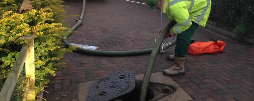 Septic tank cleaning technician servicing a septic tank with a vacuum hose in Chicago, IL