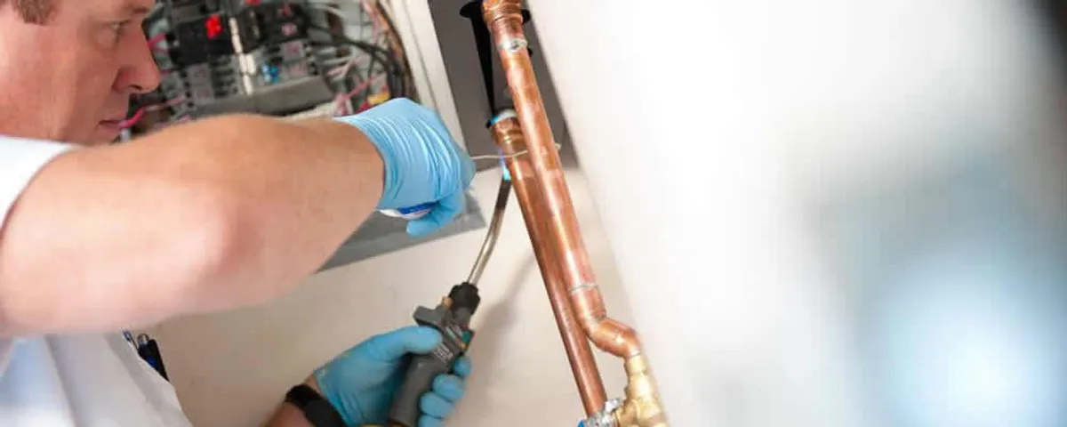 Water heater repair technician testing copper pipe connections and controls in Chicago, IL