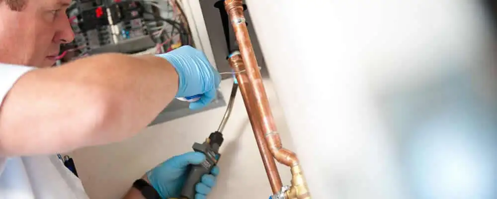 Water heater repair technician testing copper pipe connections and controls in Chicago, IL
